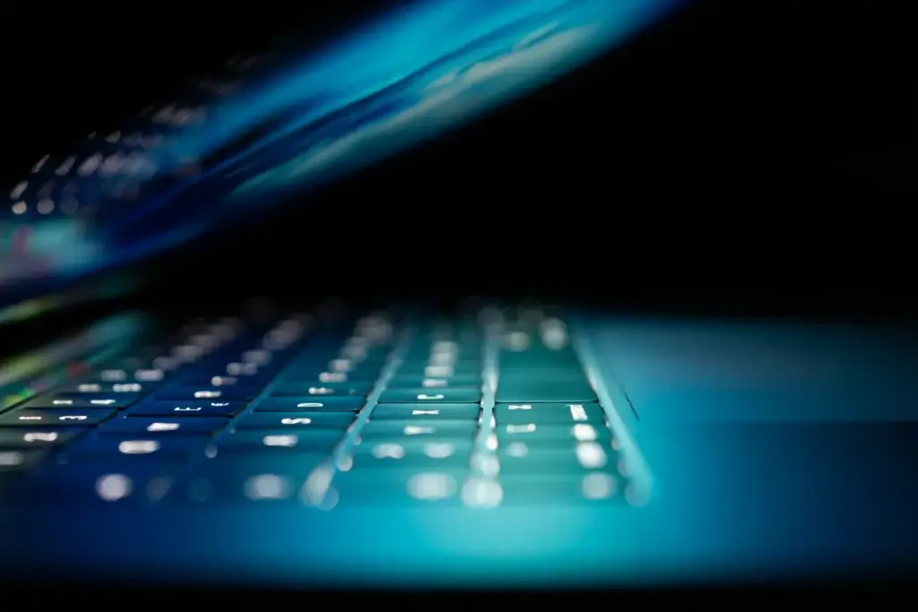 Close-up van een verlicht laptoptoetsenbord in blauw licht tegen een donkere achtergrond. Artikel voor Corsa Zakenmagazijn