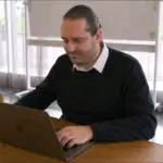 Max Salden zittend aan een bureau, achter een laptop