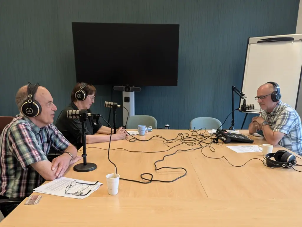 Drie personen rond een tafel de een podcast opnemen