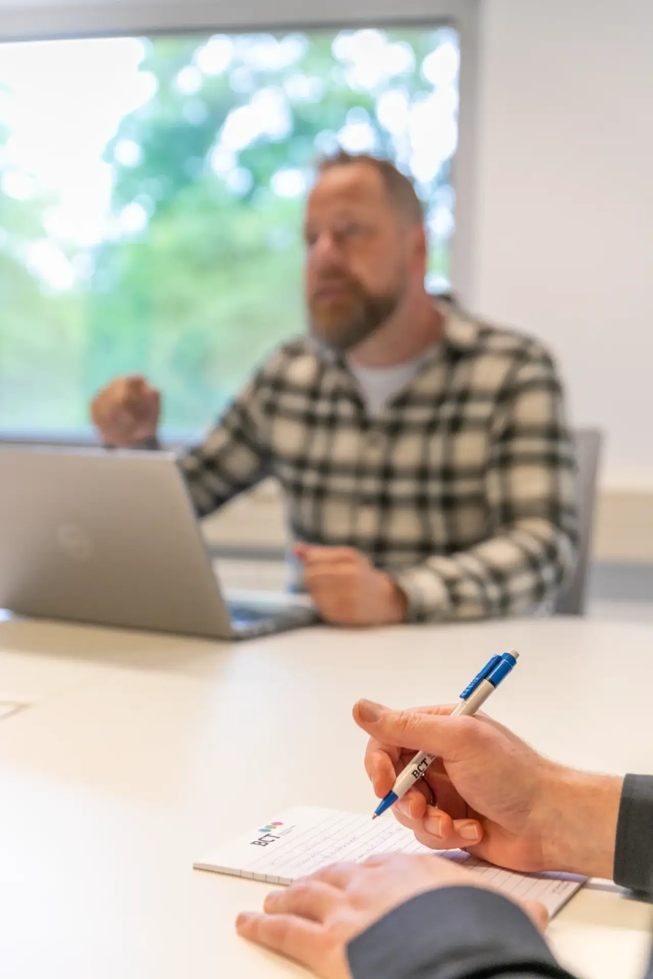 Medewerker maakt aantekeningen tijdens overleg over datakwaliteit met collega
