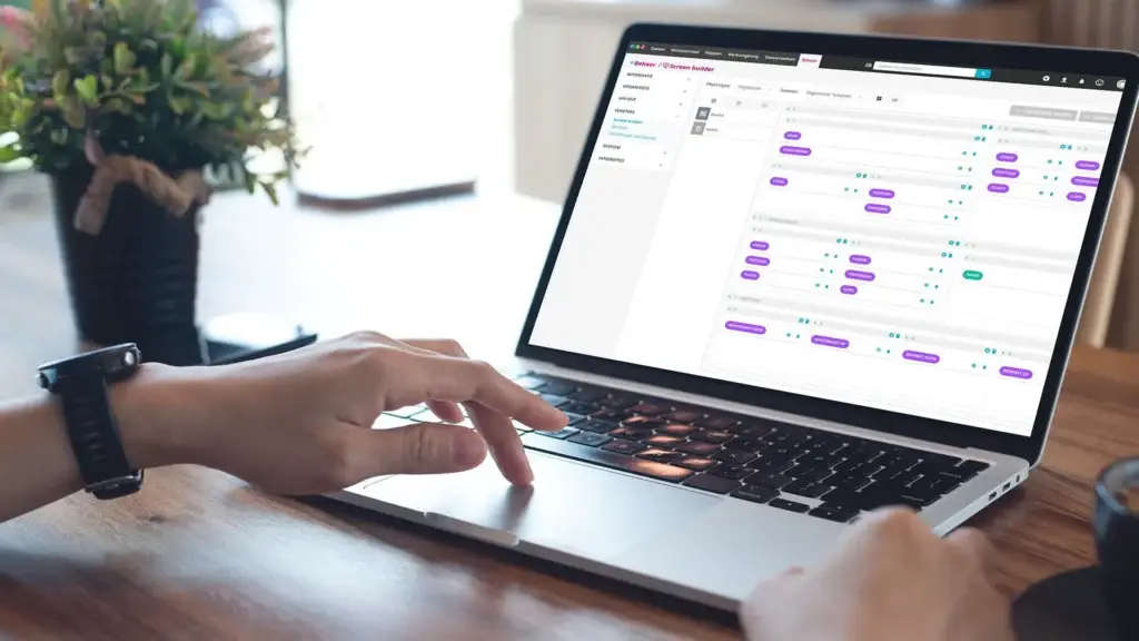 Persoon werkt op een laptop met de Corsa Screenbuilder-interface voor het inrichten van schermen en vensters.