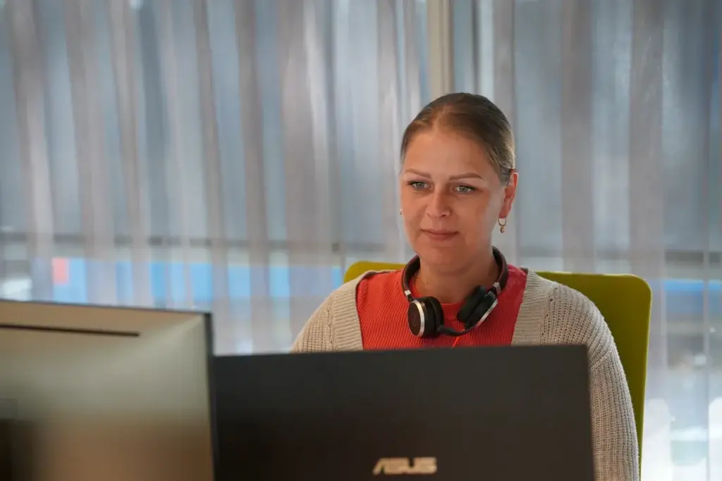 Medewerker achter laptop met koptelefoon om de nek