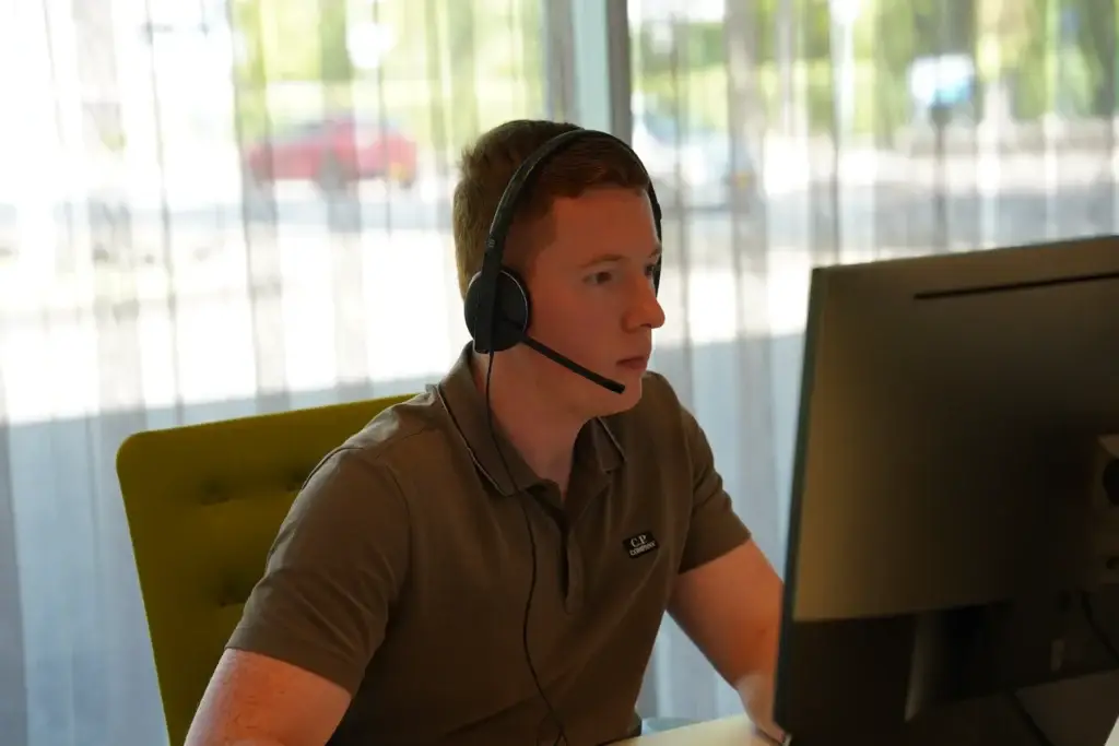 Medewerker met headset werkt geconcentreerd achter een beeldscherm bij een raam