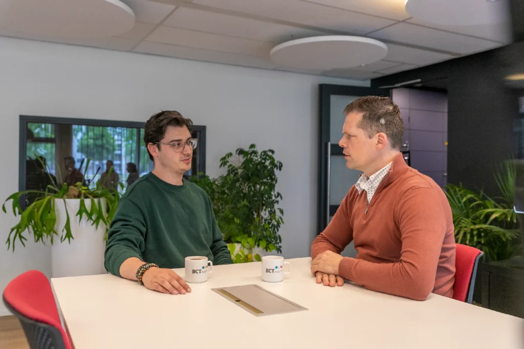 Twee Corsa-medewerkers in gesprek aan een vergadertafel met BCT-koffiebekers