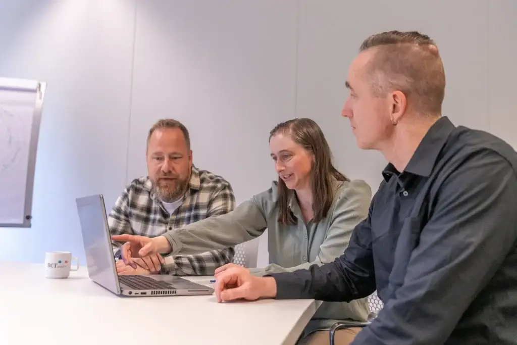 Drie collega's overleggen samen achter een laptop tijdens een werksessie