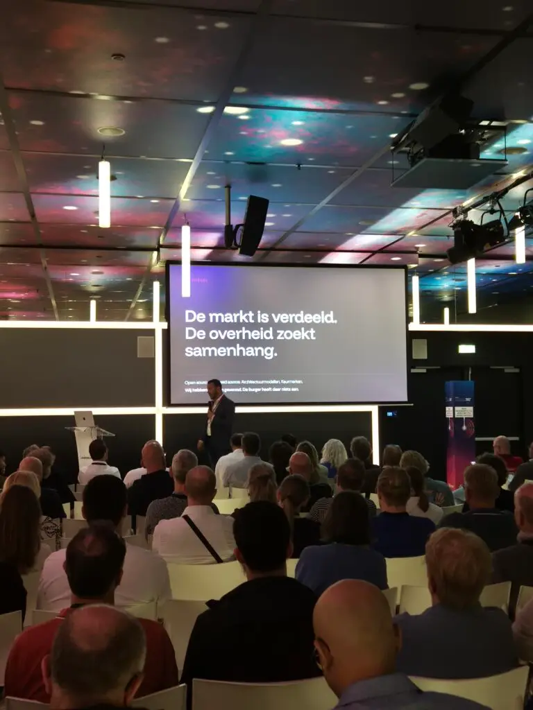 Stefan Knarren spreekt tijdens Overheid360 over Common Ground voor gemeenten, met op het scherm de tekst: de markt is verdeeld, de overheid zoekt samenhang.
