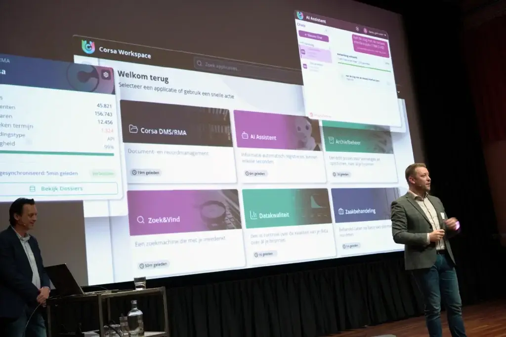 Man staat op podium voor een groot scherm met Corsa Workspace afbeelding.