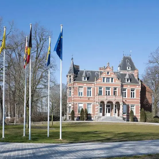 Gemeentehuis van Stabroek met vlaggenmasten en tuin, onder blauwe lucht
