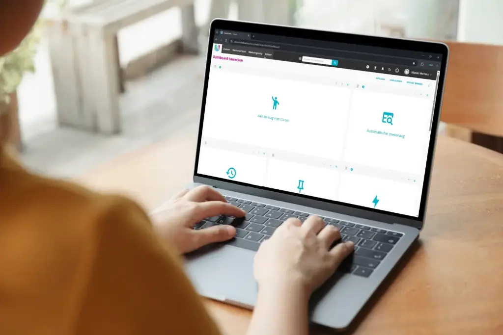 iemand typt op een laptop waarop het Corsa-dashboard in bewerkmodus te zien is, met widgets voor "Aan de slag met Corsa!" en "Automatische zoekvraag".