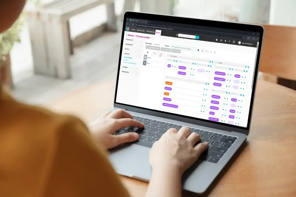 iemand typt op een laptop waarop de screenbuilder functie te zien is.